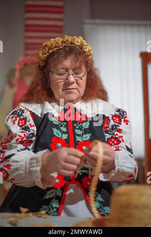 femme tisse divers jouets et vêtements de paille. l’artisanat populaire Banque D'Images