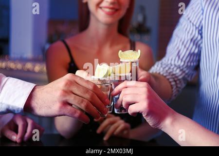 Les jeunes toasting avec des coups de Tequila mexicains au bar, gros plan Banque D'Images