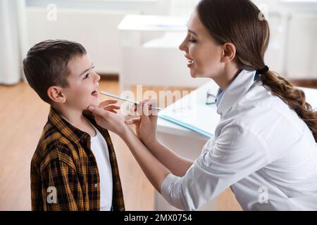 Médecin enfant examinant la gorge du petit patient en clinique Banque D'Images