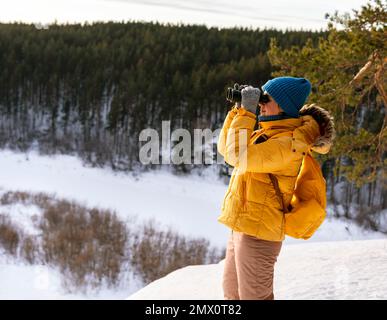 Femme écologiste avec des jumelles regardant la migration des oiseaux dans la forêt enneigée d'hiver Bird Watching Wildlife manager espace copie Banque D'Images