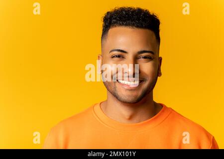 Portrait d'un jeune Indien heureux satisfait debout et regardant l'appareil photo avec un sourire léger isolé sur le jaune. Un studio d'intérieur a photographié un bel homme barbu Banque D'Images