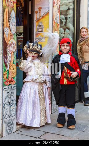 Venise, Italie - 18 février 2012 : image d'un couple déguisé d'enfants posant devant un magasin traditionnel, pendant les Journées du Carnaval de Venise. Banque D'Images