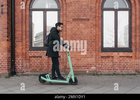 Jeune homme utilisant un scooter électrique Banque D'Images