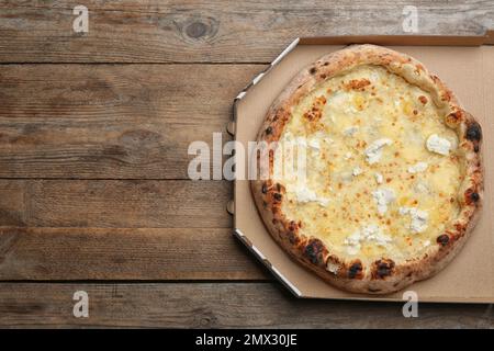 Pizza au fromage délicieuse dans une boîte à emporter sur une table en bois, vue sur le dessus. Espace pour le texte Banque D'Images