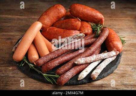 Différentes saucisses savoureuses servies sur une table en bois Banque D'Images