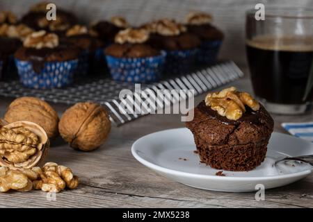 Muffins aux noix fraîchement cuits sur un porte-gâteau et noix avec une tasse de café Banque D'Images