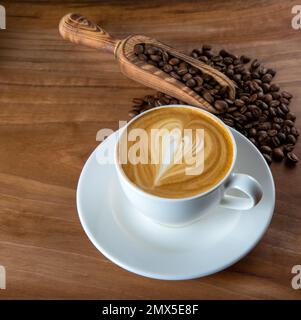 Grains de café rôtis avec latte et motif coeur en mousse Banque D'Images