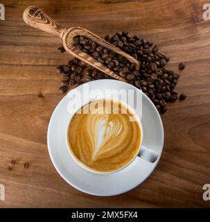 Grains de café rôtis avec latte et motif coeur en mousse Banque D'Images