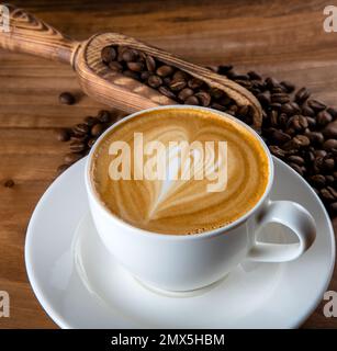 Grains de café rôtis avec latte et motif coeur en mousse Banque D'Images