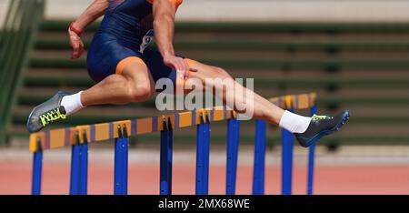 Un athlète qui exécute une course de haies dans un stade, un coureur qui saute sur un haies lors d'un événement sur piste ou sur le terrain Banque D'Images