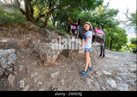 Fille à cheval sur un âne pour visiter la grotte de Diktaion Andron. Touristes visitingcélèbre grotte Diktaion Andron, le lieu de naissance de dieu Zeus dans le plateau de Lasithi, CRE Banque D'Images