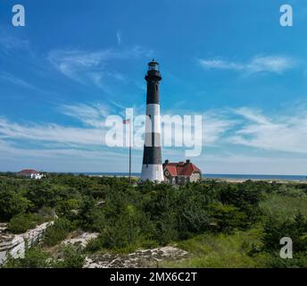 Vue depuis le haut du phare de Fire Island prise d'un drone sur le côté de la baie avec ciel bleu et mondes wispy en arrière-plan. Banque D'Images