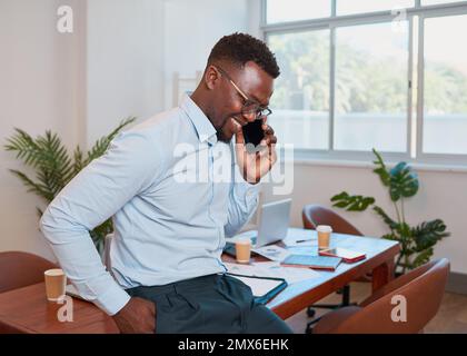 Le jeune homme d'affaires noir est assis sur une table de conférence pour passer un appel souriant Banque D'Images