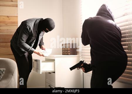 Dangereux criminels masqués avec des armes qui volent de l'argent de la maison Banque D'Images