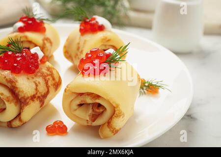 Crêpes fines délicieuses avec caviar rouge sur l'assiette, en gros plan Banque D'Images