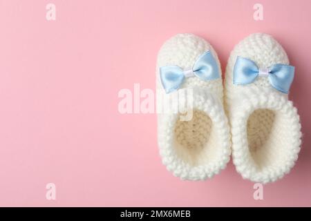 Chaussons faits main pour enfant sur fond rose, plat avec espace pour le texte Banque D'Images