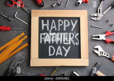 Tableau noir avec des mots HAPPY PATHER'S DAY et des outils sur fond de pierre grise, plat Banque D'Images