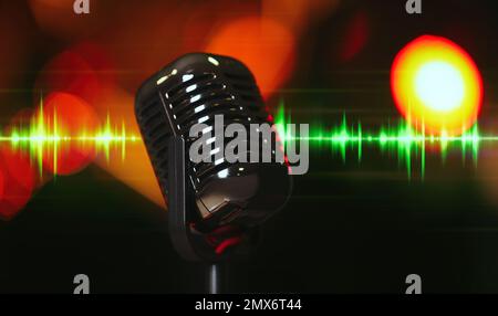 Microphone et onde radio sur fond sombre, effet bokeh Banque D'Images