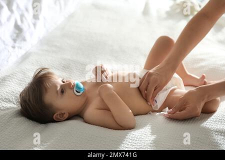 La mère change la couche de bébé sur le lit à la maison Banque D'Images