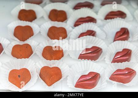 Pâtisserie au chocolat de la Saint-Valentin et verre de boulangerie exposition de truffes individuelles faites à la main en forme de lèvres et de coeurs pour la Saint-Valentin Banque D'Images