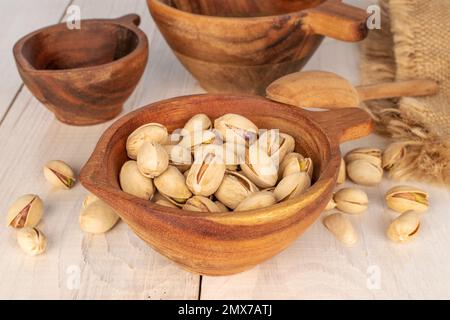 Quelques pistaches non décortiquées dans une tasse en bois sur une table en bois, gros plan. Banque D'Images