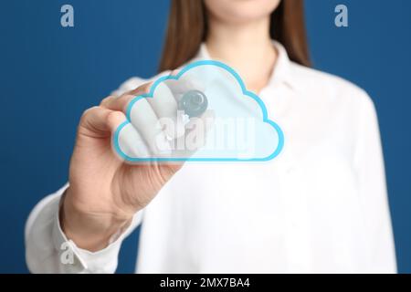 Femme pointant vers l'icône de nuage virtuel sur fond bleu, gros plan de la main. Concept de stockage des données Banque D'Images