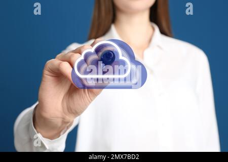 Femme pointant vers l'icône des nuages virtuels sur fond bleu, gros plan de la main. Concept de stockage des données Banque D'Images