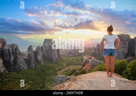 Jeune femme en t-shirt blanc debout en face de Grèce Meteora montagnes, monastère et village en arrière-plan Banque D'Images