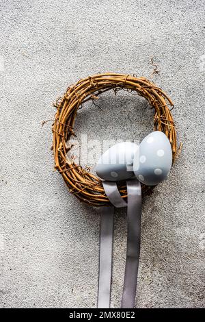 Concept de vacances de pâques avec couronne de vigne décorée d'un ruban bleu pâle sur fond de béton gris Banque D'Images