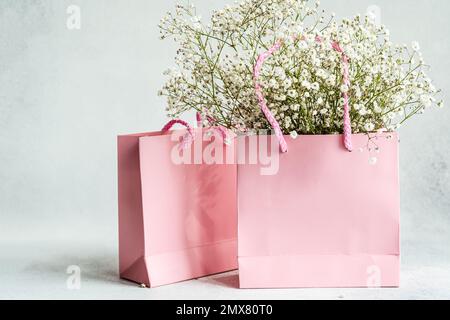 Sacs en papier rose et fleurs blanches de Gypsophila comme un concept de shopping Banque D'Images