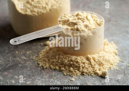 Poudre de protéine de lactosérum aromatisée à la vanille dans une cuillère de mesure en plastique Banque D'Images