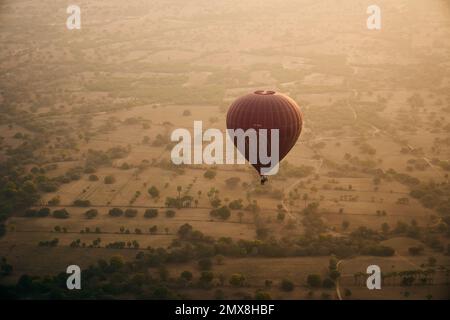 Vue aérienne d'une seule montgolfière survolant un groupe de temples Shan au lever du soleil à Bagan, Myanmar (Birmanie). Banque D'Images
