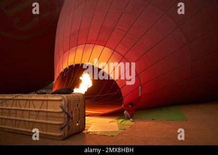 Un ballon d'air chaud rouge s'enflamme et se gonfle au lever du soleil à Bagan, au Myanmar (Birmanie). Banque D'Images