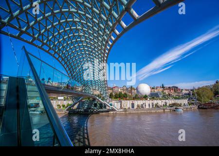 Vue sur le parc Rike - jour ensoleillé du printemps. Terrasse d'observation sous le nouveau pont piétonnier (pont de la paix) et la rivière Kura - un écoulement rapide de la montagne brune Banque D'Images