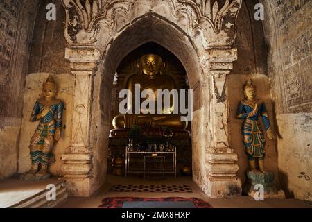 Une grande statue de Bouddha d'or assise dans un ancien temple à Bagan, Myanmar (Birmanie). Banque D'Images