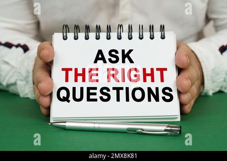 Un homme tient un bloc-notes dans ses mains avec l'inscription - poser les bonnes questions. Banque D'Images