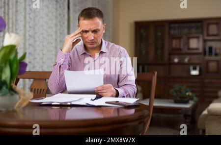Triste homme frustré à à bout de papier à la table Banque D'Images