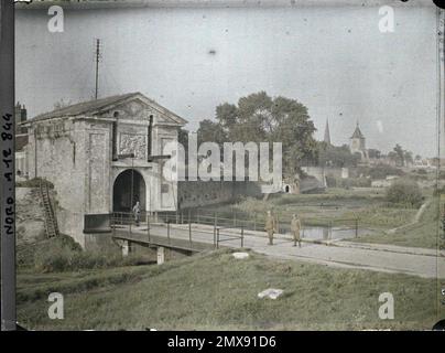 Bergues, Nord, France , 1917 - Nord de la France, Belgique - Paul Castelnau (section photographique des armées) - (1-5 septembre). Façade arrière, uniforme militaire, clocher, lande, arrière, architecture fortifiée, porte, renaissance, décor sculpté, rempart, Pont, homme, première Guerre mondiale, vêtements, logement , Architecture, art, êtres humains, France, porte des remparts Banque D'Images