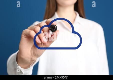 Femme pointant vers l'icône de nuage virtuel sur fond bleu, gros plan de la main. Concept de stockage des données Banque D'Images