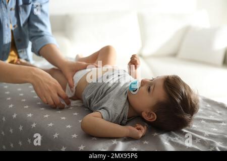 La mère change la couche de bébé sur la table à la maison Banque D'Images