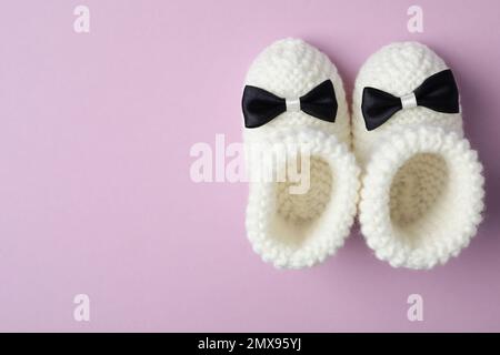 Chaussons faits main pour enfant sur fond violet, plat avec espace pour le texte Banque D'Images