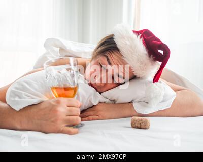 L'homme dans le chapeau de Santa essaie de rafraîchir la hanche après la fête d'alco. Il souffre de maux de tête après le nouvel an ou la fête de Noël. Bonjour. Al Banque D'Images
