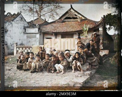 Thanh-Tri, Tonkin, Indochine Un groupe de villageois (principalement des enfants) assis devant le temple bouddhiste, connu sous le nom de "pagode de la maison de rire, Léon occupé à Indochine Banque D'Images