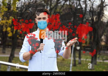 Journaliste avec masque médical présentant des nouvelles pendant l'épidémie de coronavirus. Carte du monde démontrant la propagation de la maladie Banque D'Images