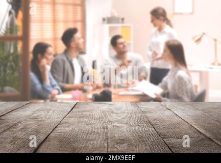 Surface en bois vide et vue floue des designers d'intérieur professionnels travaillant au bureau, en gros plan. Espace pour le texte Banque D'Images