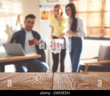 Surface en bois vide et vue floue des designers d'intérieur professionnels travaillant au bureau, en gros plan. Espace pour le texte Banque D'Images