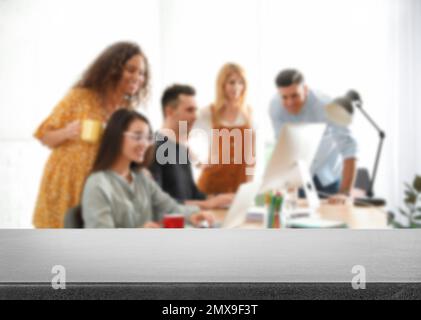 Surface en pierre vide et vue floue des designers d'intérieur professionnels travaillant au bureau, en gros plan. Espace pour le texte Banque D'Images