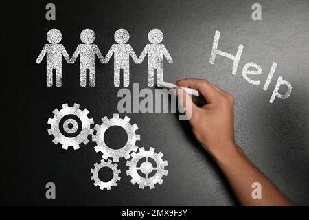 Concept de travail d'équipe. Homme dessinant des personnages sur un tableau noir Banque D'Images