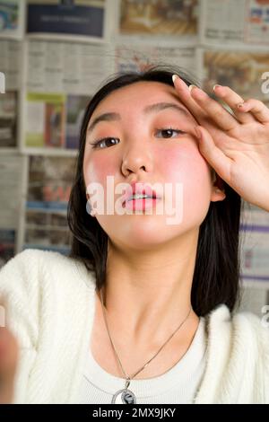 Gros plan portrait de la belle adolescente asiatique avec les mains encadrant le visage Banque D'Images