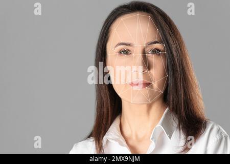 Système de reconnaissance faciale. Femme mature avec grille de lecture d'identification biométrique sur fond gris Banque D'Images